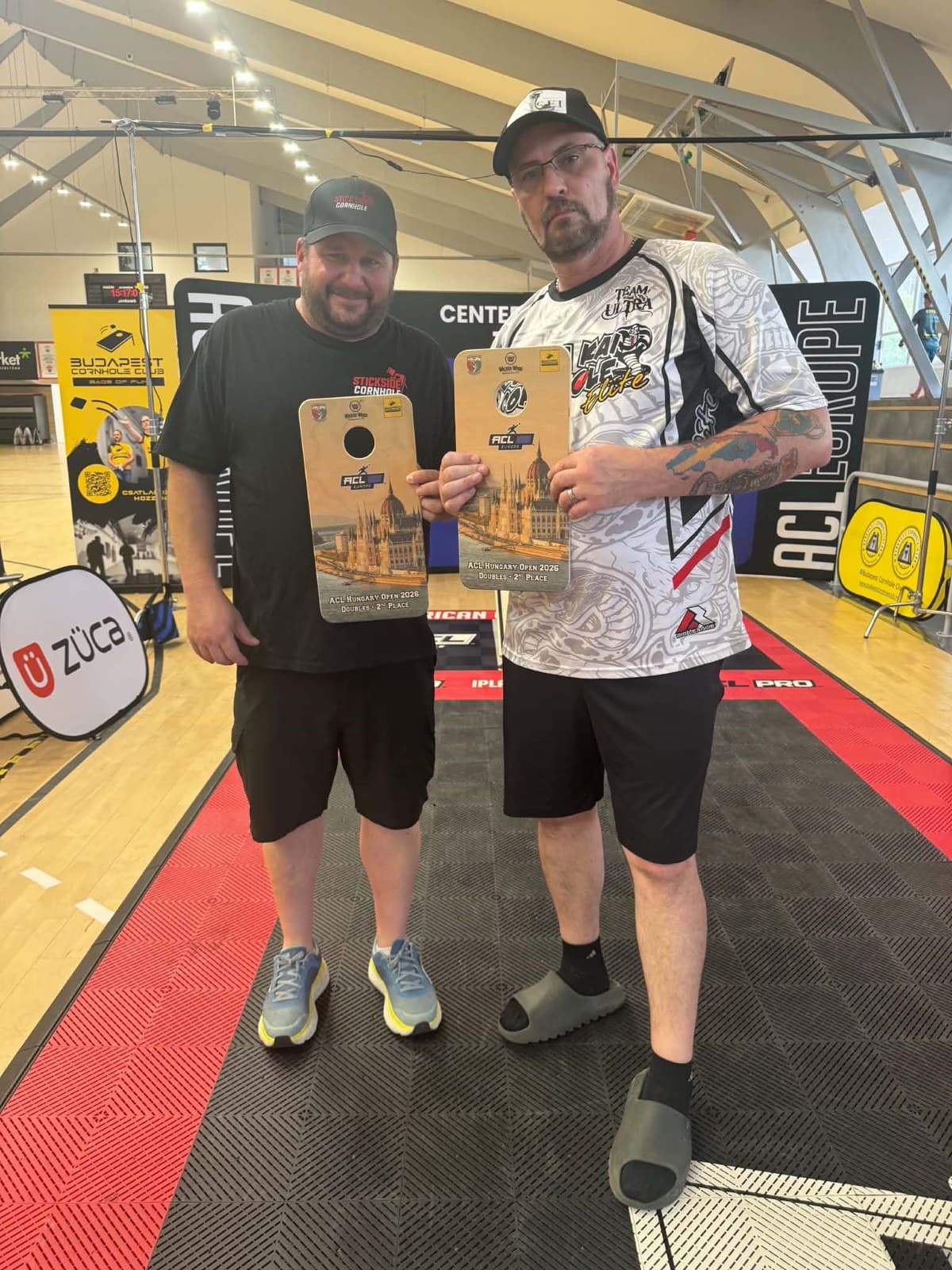 Denny Mallon in a Stickside Cornhole tee holding his Doubles 2nd Place board at the ACL Hungary Open 2026